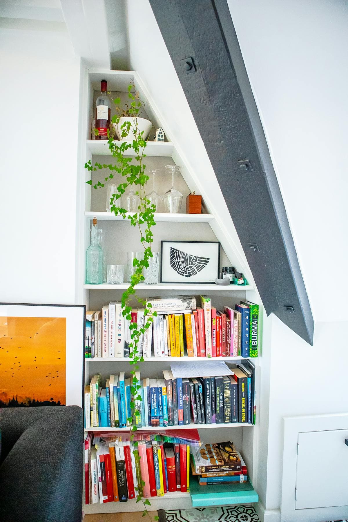 Tapered under-stairs bookshelf in sprayed white with integrated drinks display in Port Erin.