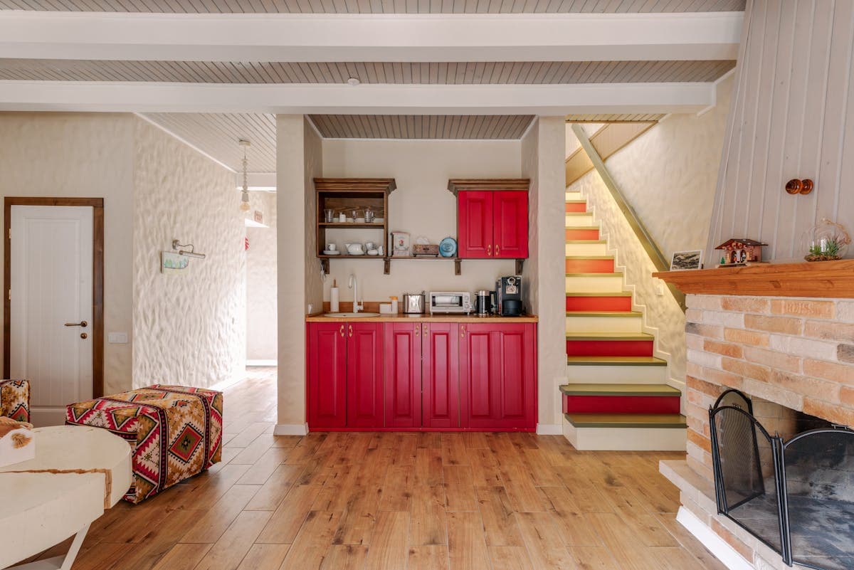 Painted-red shaker doors and matching wall units beneath the staircase in Onchan.